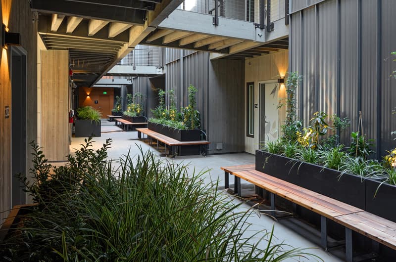 The ground floor interior walkway of a building with benches and planters