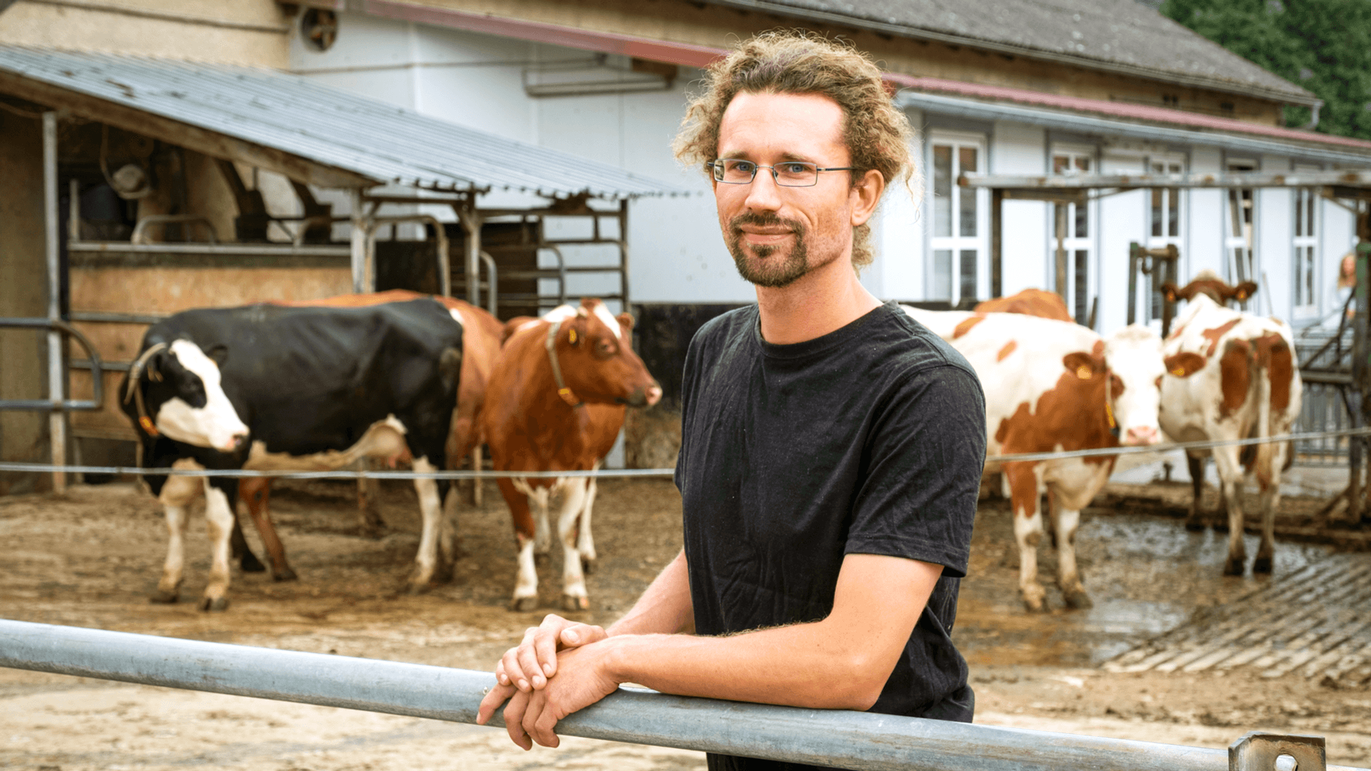 Mann mit Brille steht vor einem Kuhgehege