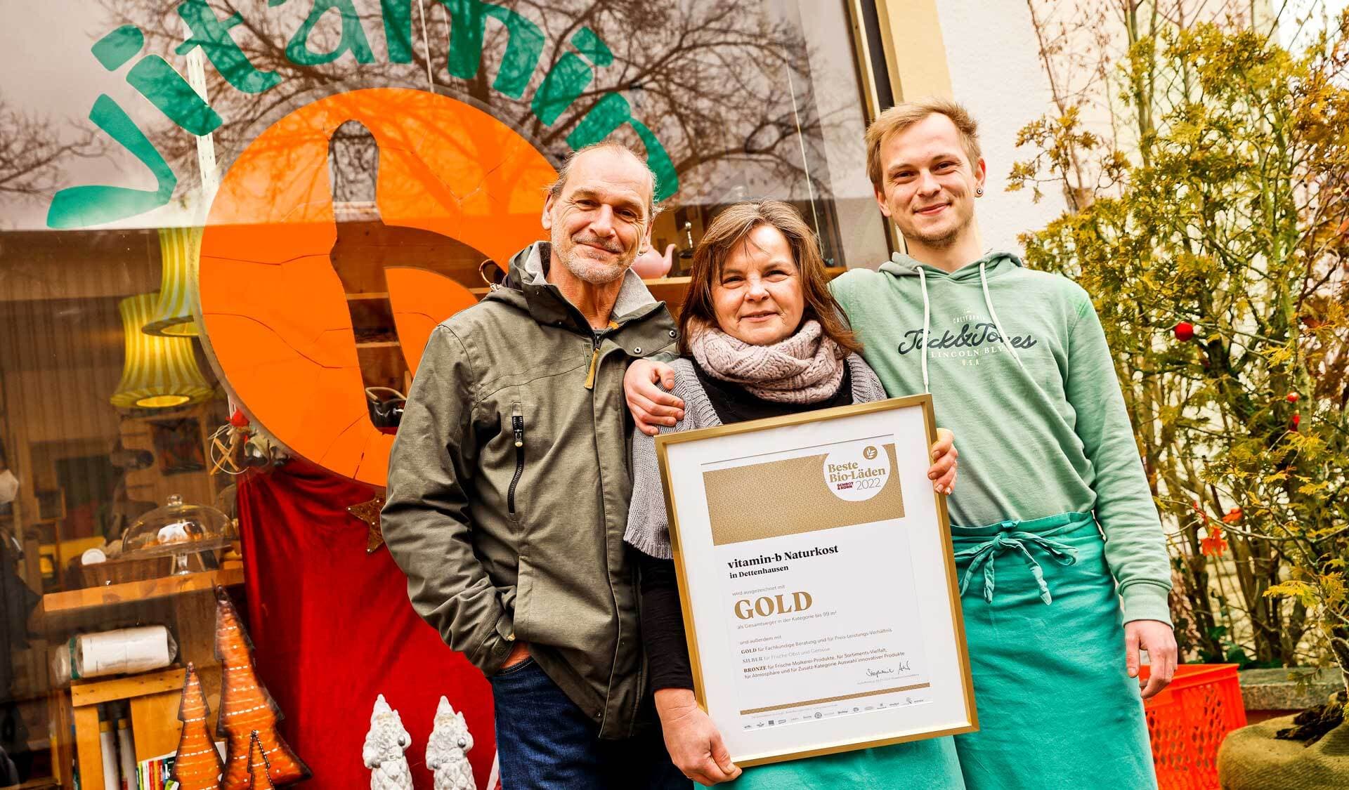 Ursula Wagner mit Ehemann Ulf, Sohn Jannik halten vor dem Vitamin b die Gold-Auszeichnung als „Bester Bio-Laden 2022“ in der Hand.