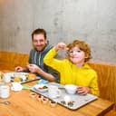 Vater im grünen Pulli und Sohn im gelben Pulli genießen das Frühstück in der Jugendherberge