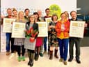 Mitarbeiter der fünf Siegerläden der Schrot&Korn-Leserwahl "Beste Bio-Läden" 2020 stehen auf einer Bühne und präsentieren stolz ihre Trophäen und Urkunden