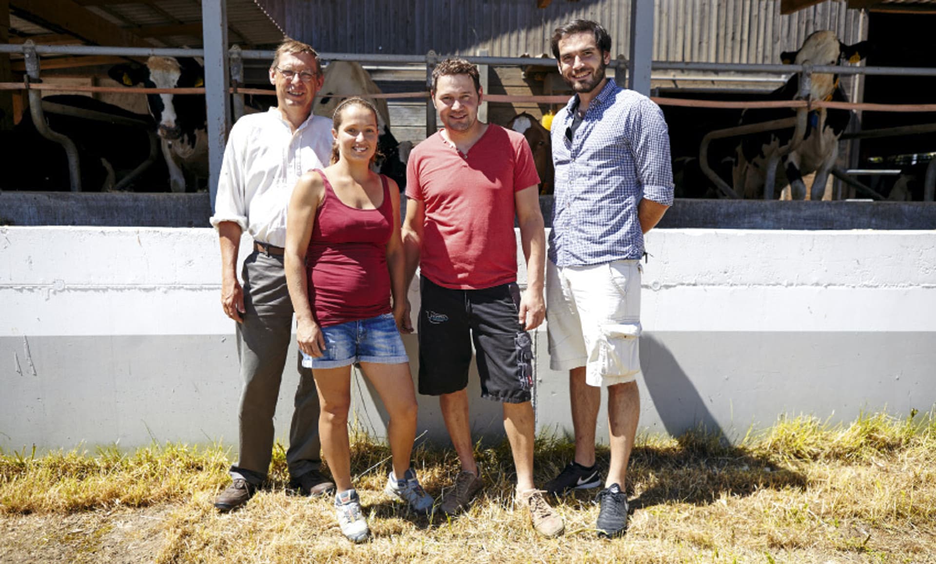 Eine Frau und drei Männer stehen vor einem Kuhstall