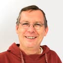 Ein Mann mit Brille vor grauem Hintergrund