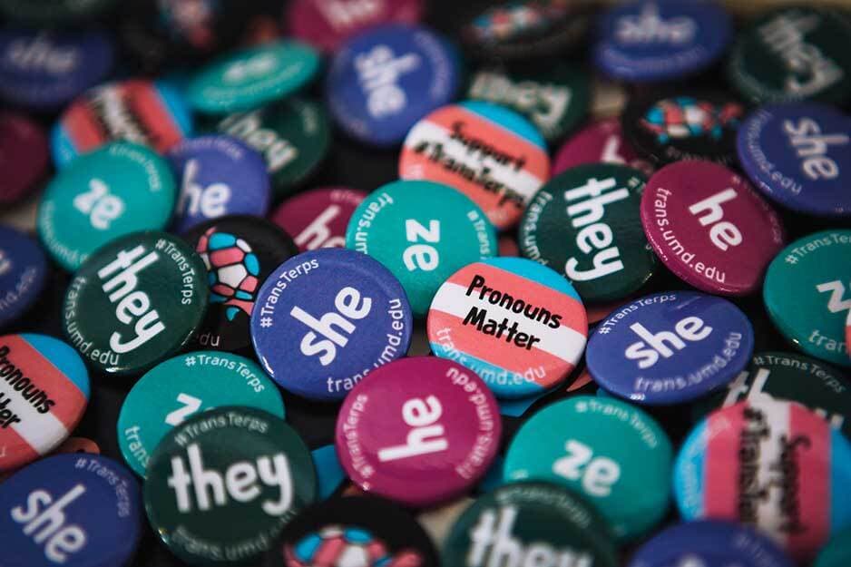 Small buttons of all different colors with different pronouns on them including they, she, he, ze, and others.