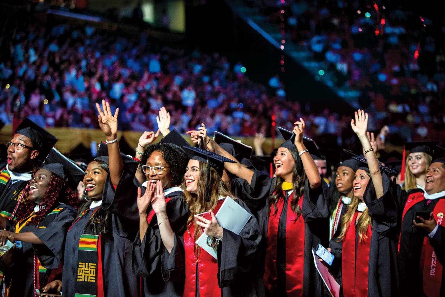 A diverse group of students in caps and gowns celebrates commencement.