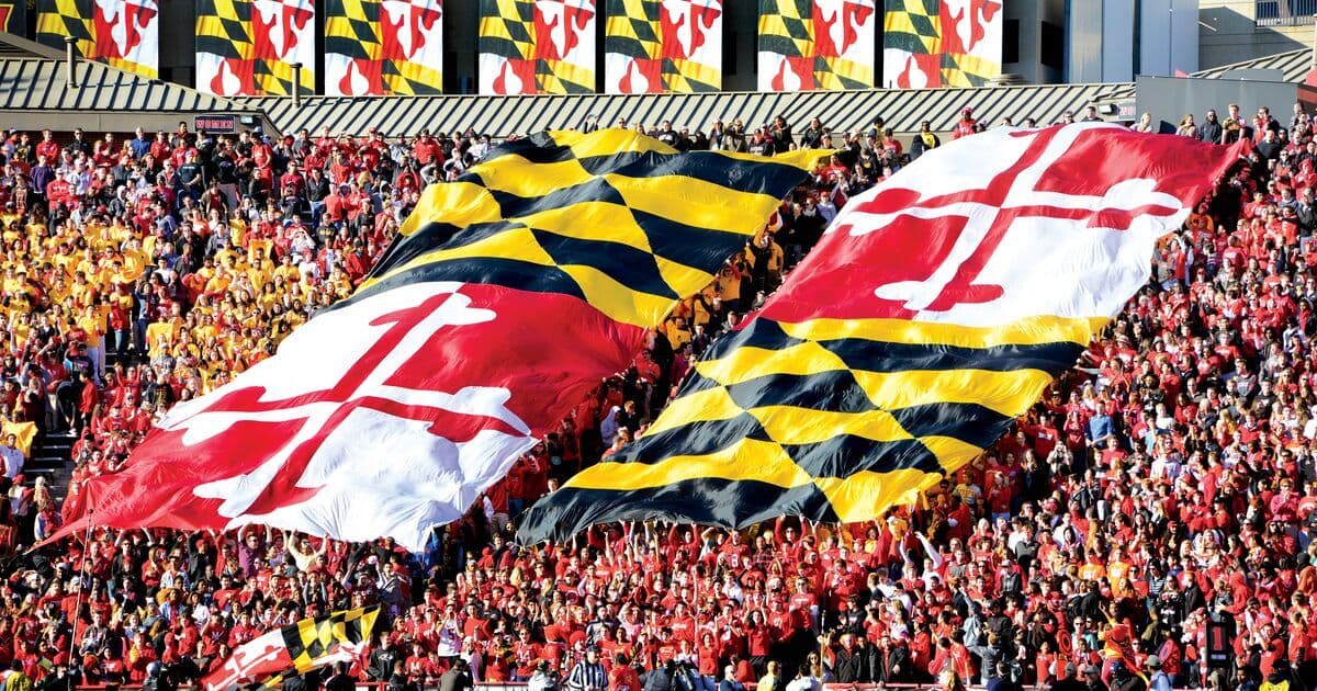 Students cheering at football game with Maryland flags