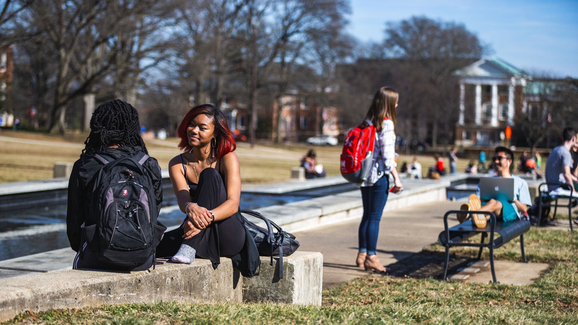 Students sit, stand, and lounge in the benches along the UMD mall.
