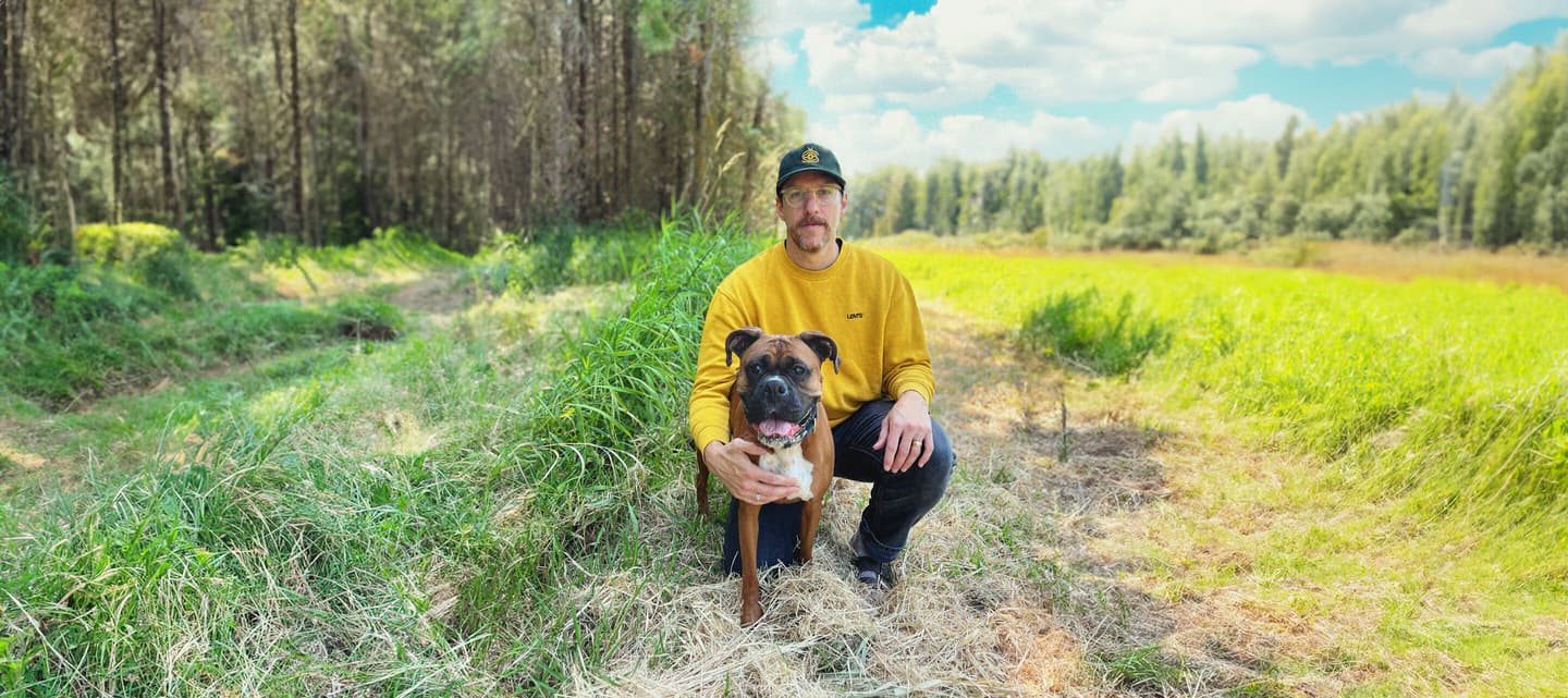 Man sitting in a grassy field with his dog.