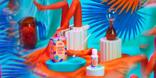 A product shot of 'High CBD Oil' in a scene with silk sheets, candles, and bright colored shapes. 