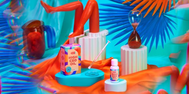 A product shot of 'High CBD Oil' in a scene with silk sheets, candles, and bright colored shapes.