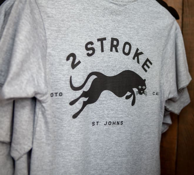 A close-up of a gray shirt with the Two Stroke logo on it.