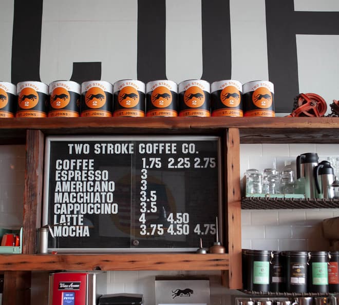 A row of coffee cans sit above the coffee shop menu.