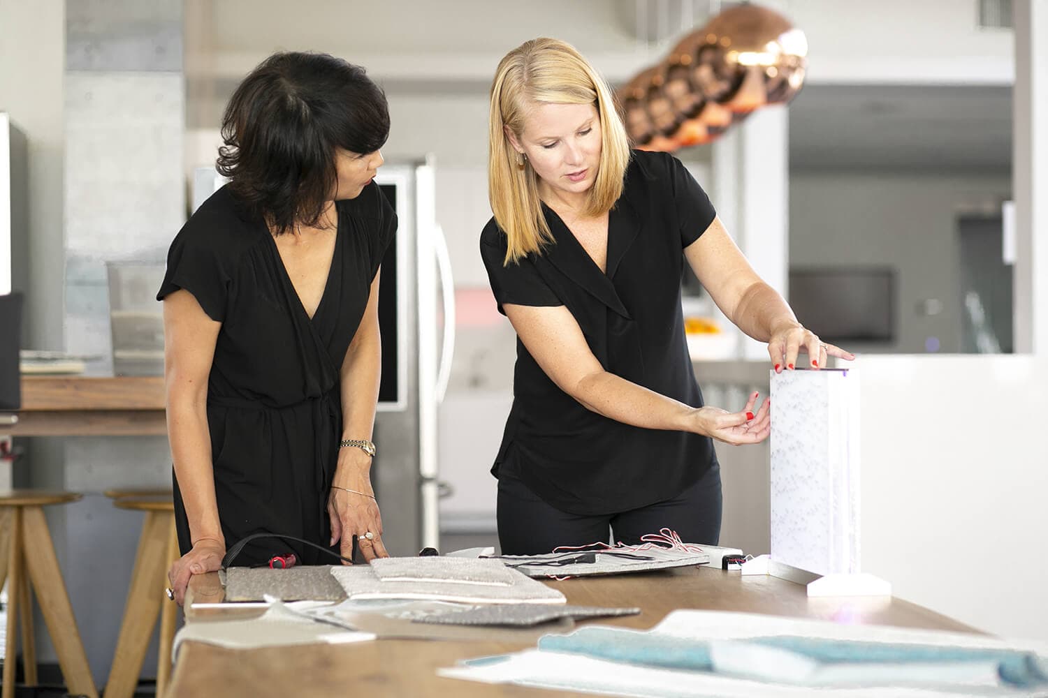 Two women in black outfits reviewing materials samples