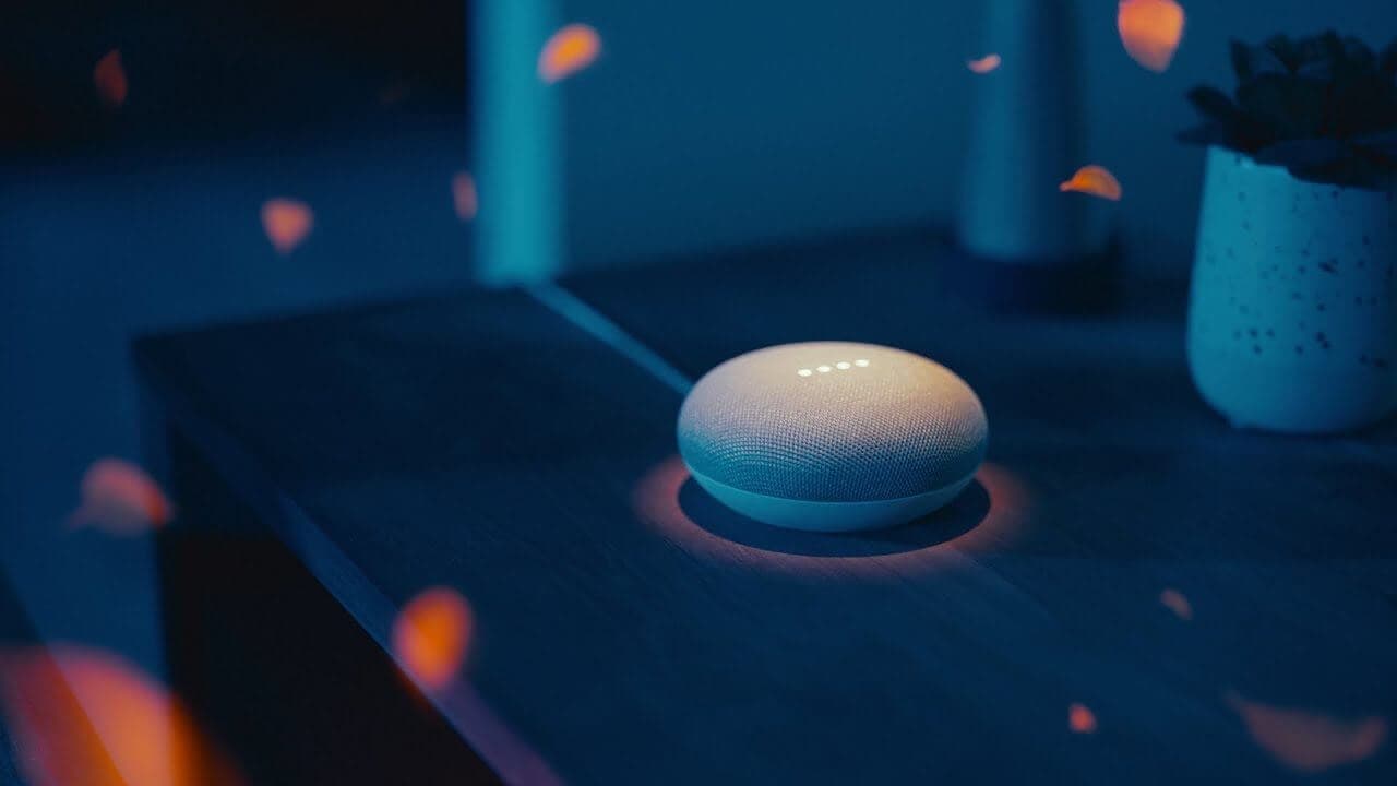Google Home Mini sitting on table in darkly lit room