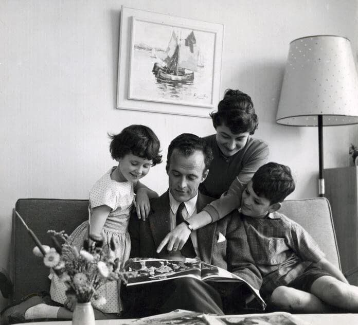 Traditional 1950s family gather on a sofa for family reading time