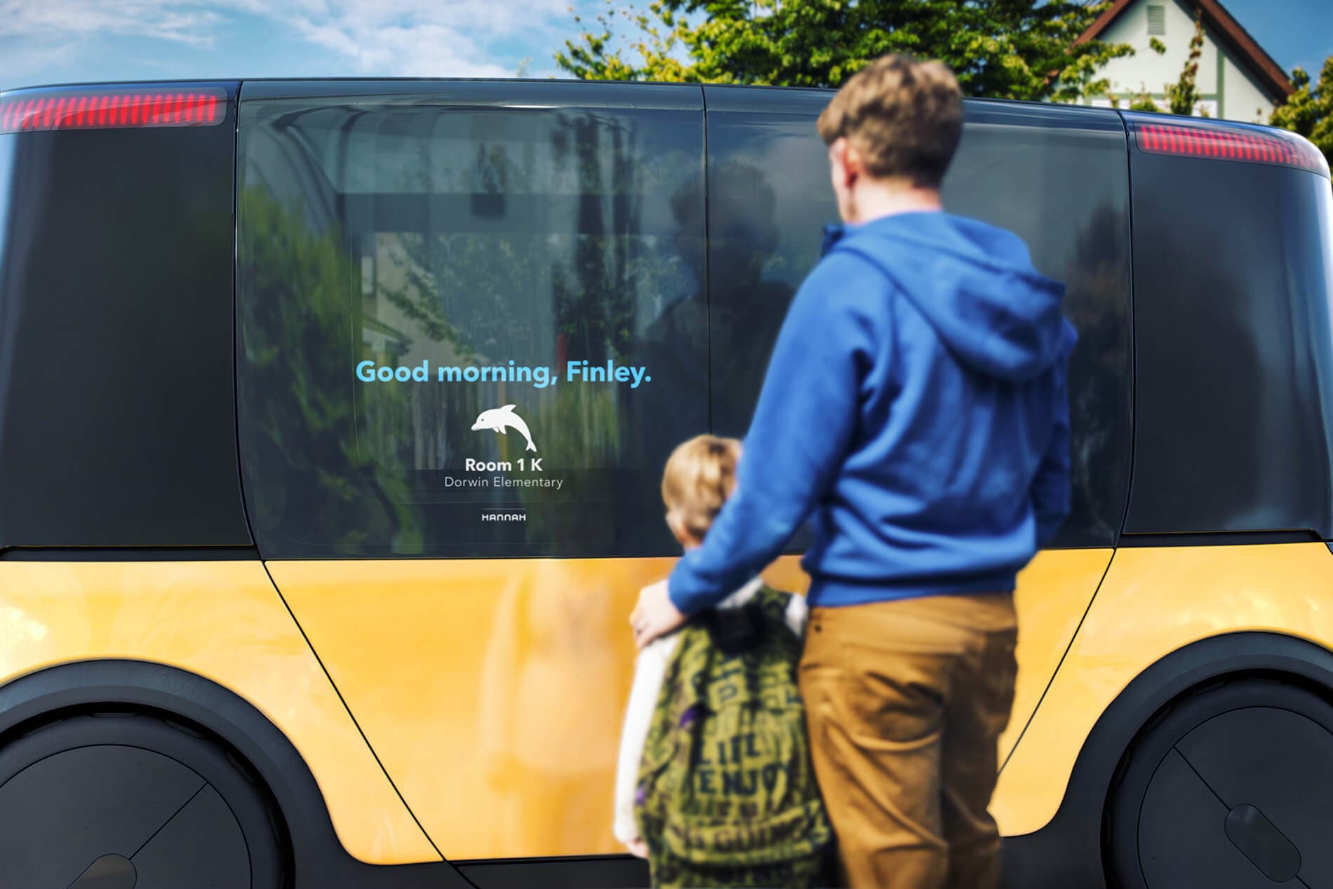 Man standing with boy in front of Hannah school bus with digital welcome screen