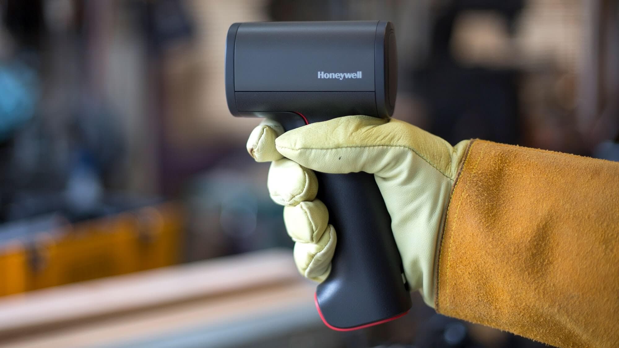 Man wearing work glove holding black scanning device
