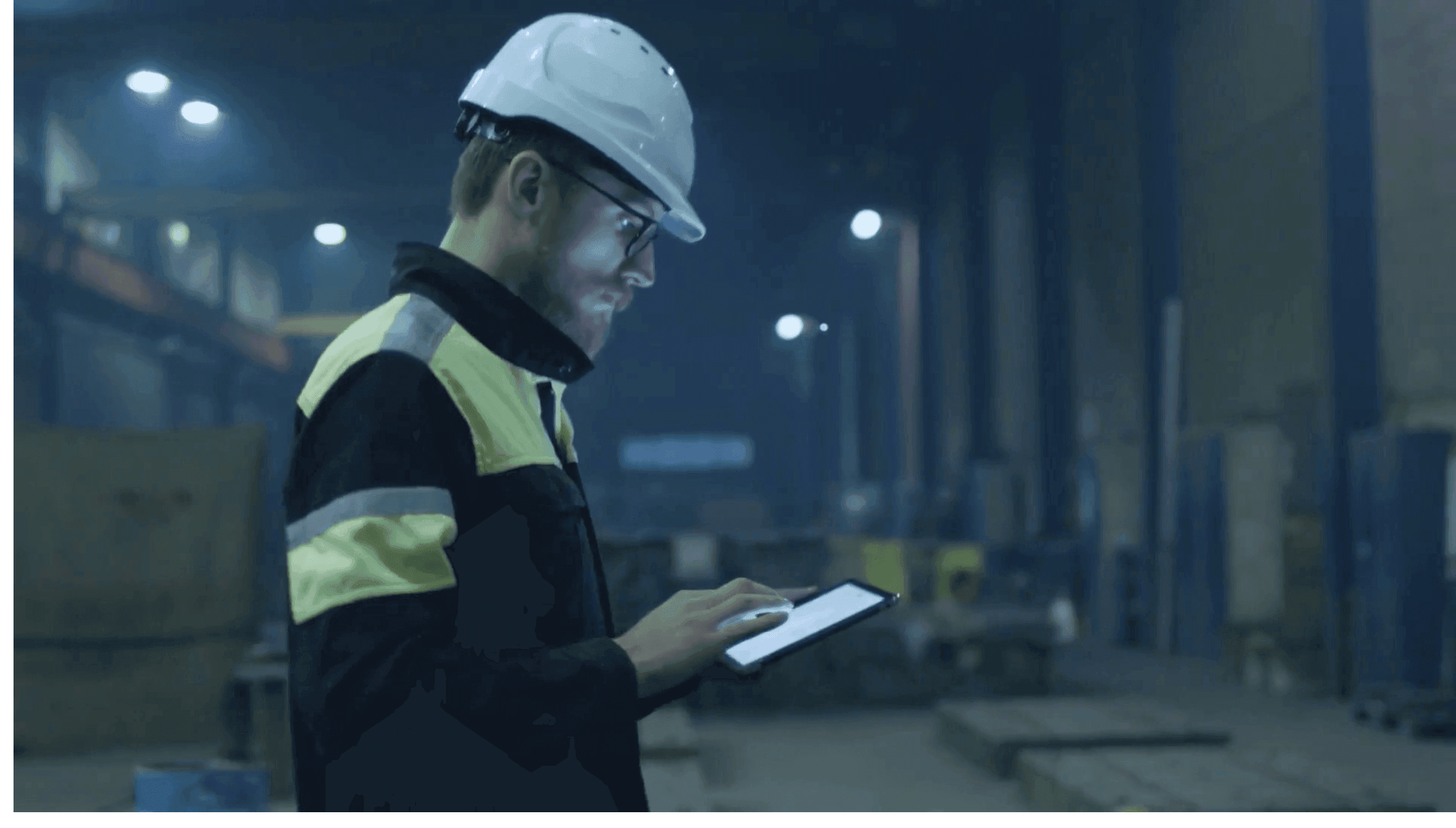 Man in hard hat walking through warehouse looking at a tablet