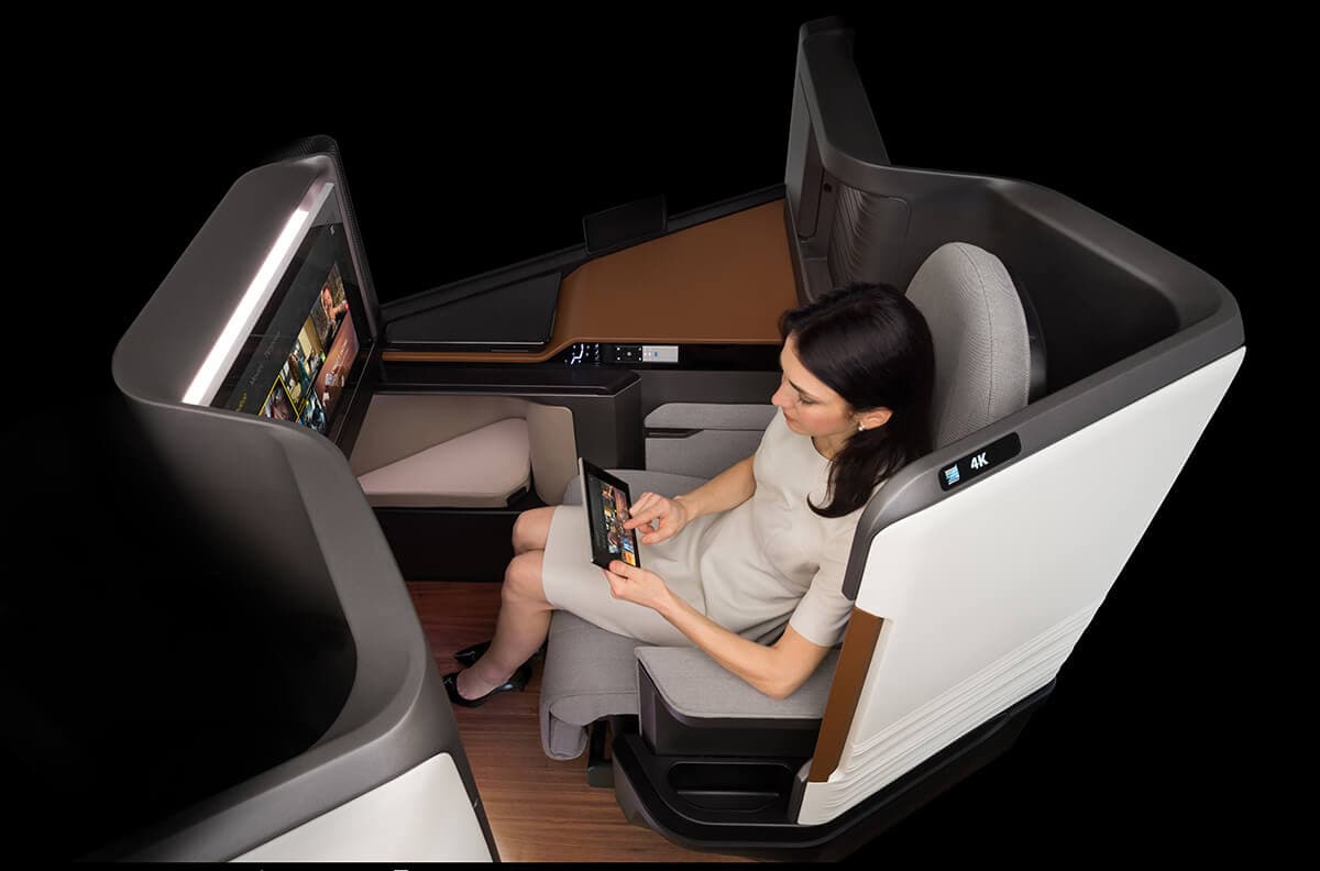 Women sitting in Business Class seat with a handheld tablet connected to the inflight entertainment system