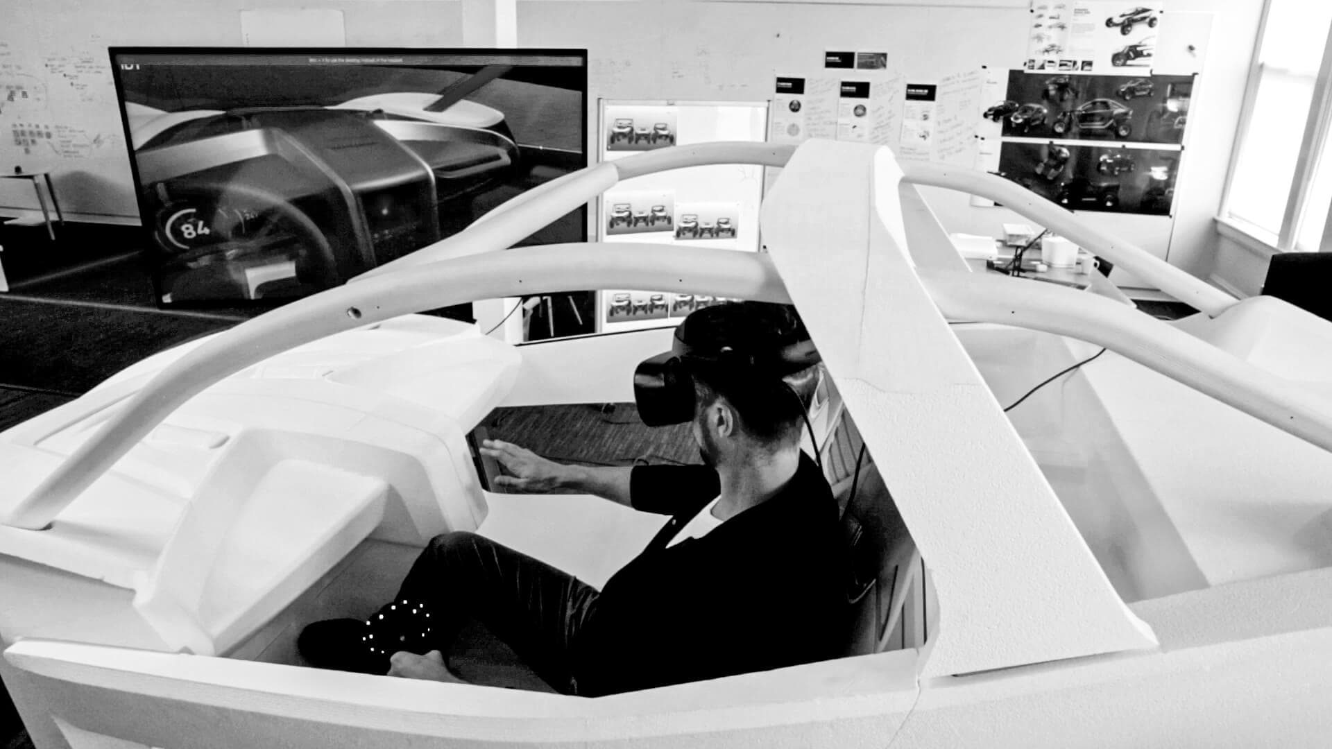 Man sitting in foam car design mock up wearing VR goggles
