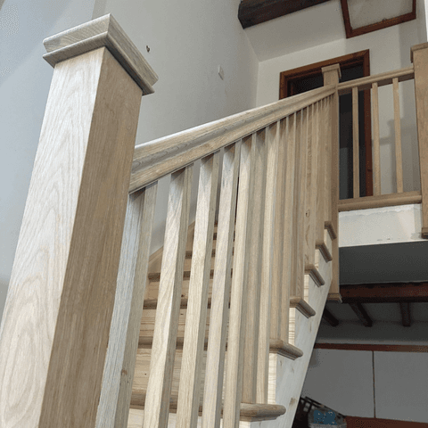 A wooden staircase rail with a handrail and spindles, providing support and safety while ascending or descending stairs.
