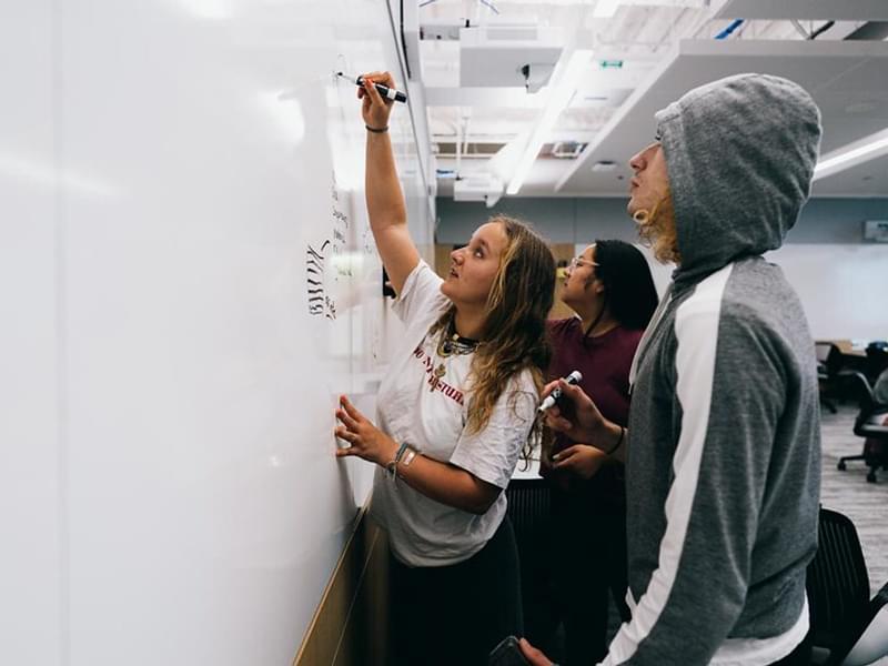 A group of students work together on a whiteboard in an ECSC classroom
