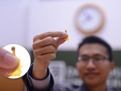 Professor Hui Fang holds up a tiny probe a little larger than the tip of a finger in his index finger and thumb