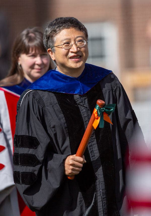Professor Jifeng Liu smiles as he walks with other faculty in procession