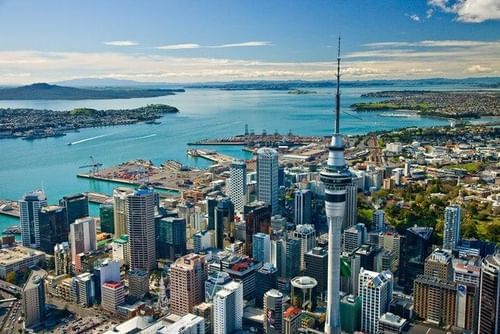 Aerial view of Auckland, New Zealand, with the Sky Tower, overlooking the harbor and surrounding landscape.