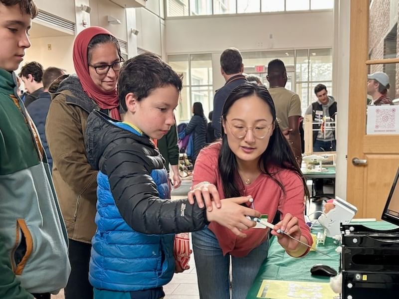 An engineering graduate student helps a visitor with a hands-on research demonstration.