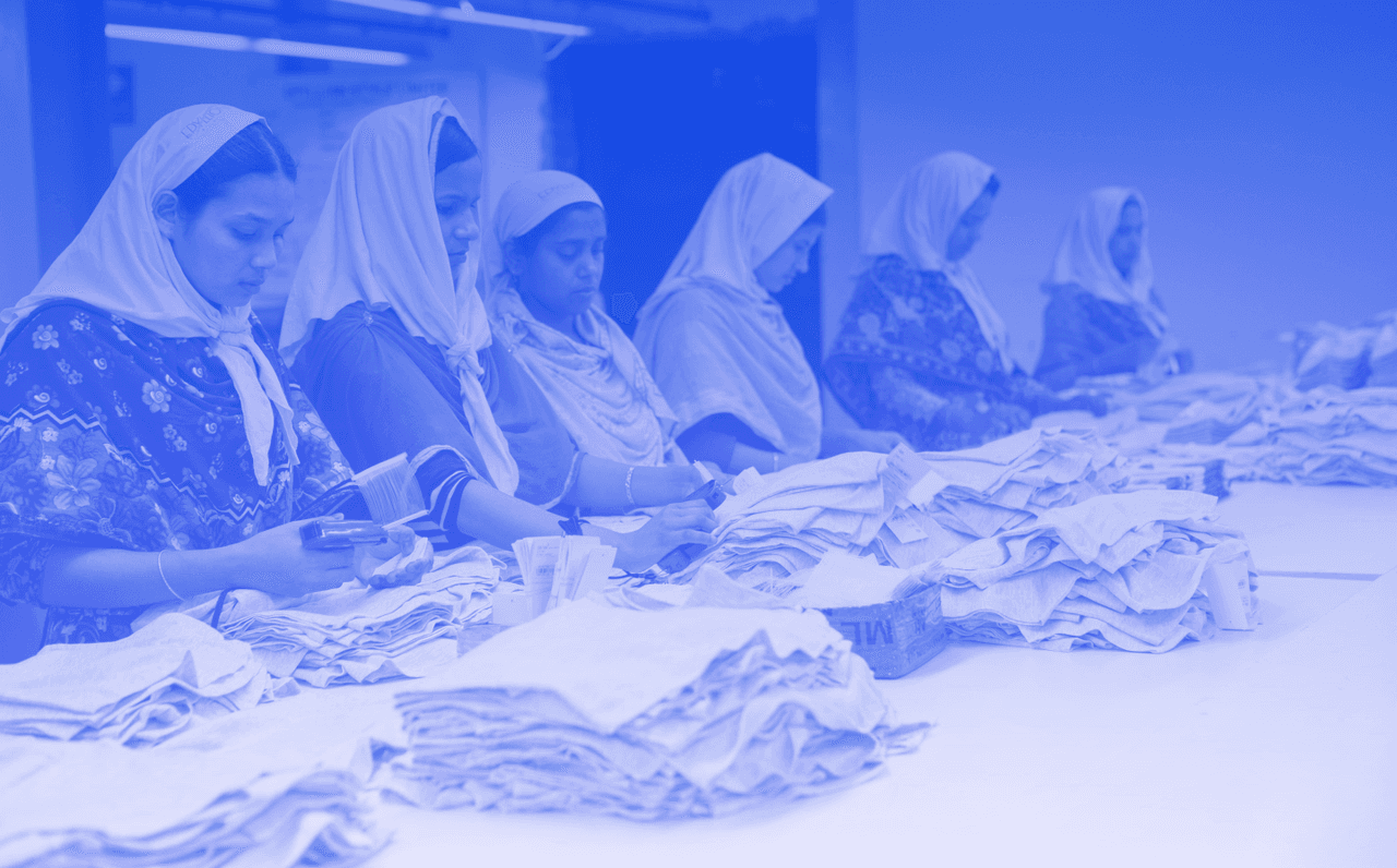 Image shows several female factory workers working with a blue filter.