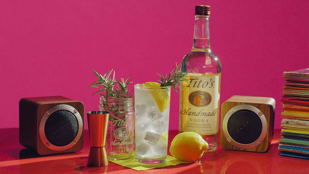 Tito's Charred Vinyl cocktail, a bottle of Tito's Vodka, a stack of records and two speakers