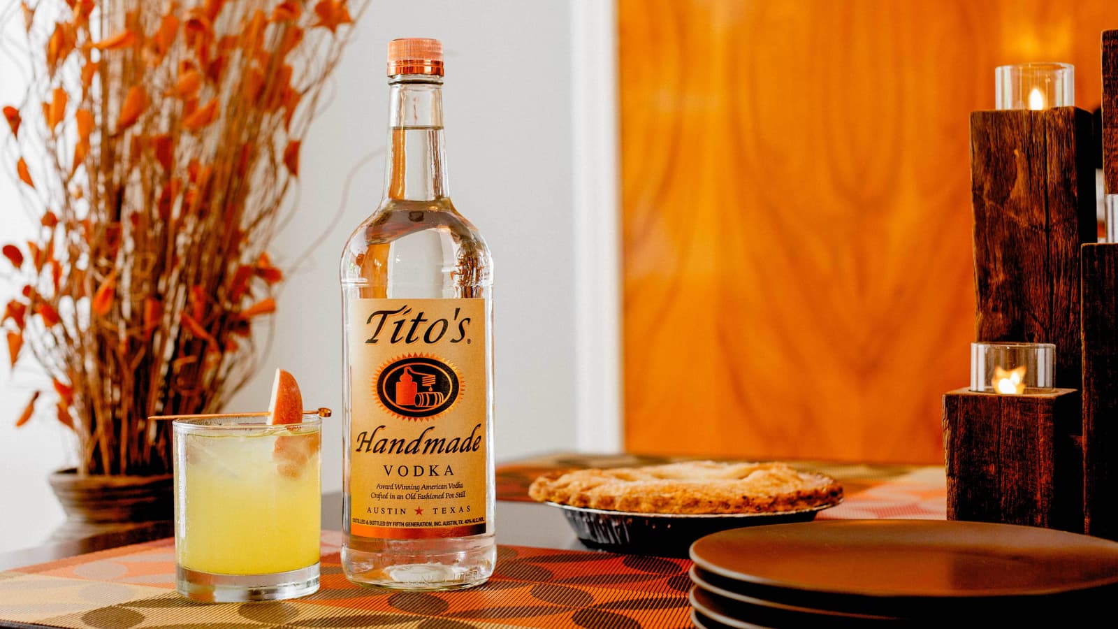 Tito's vodka bottle next to Tito's Easy as Pie cocktail in a rocks glass next to a pie