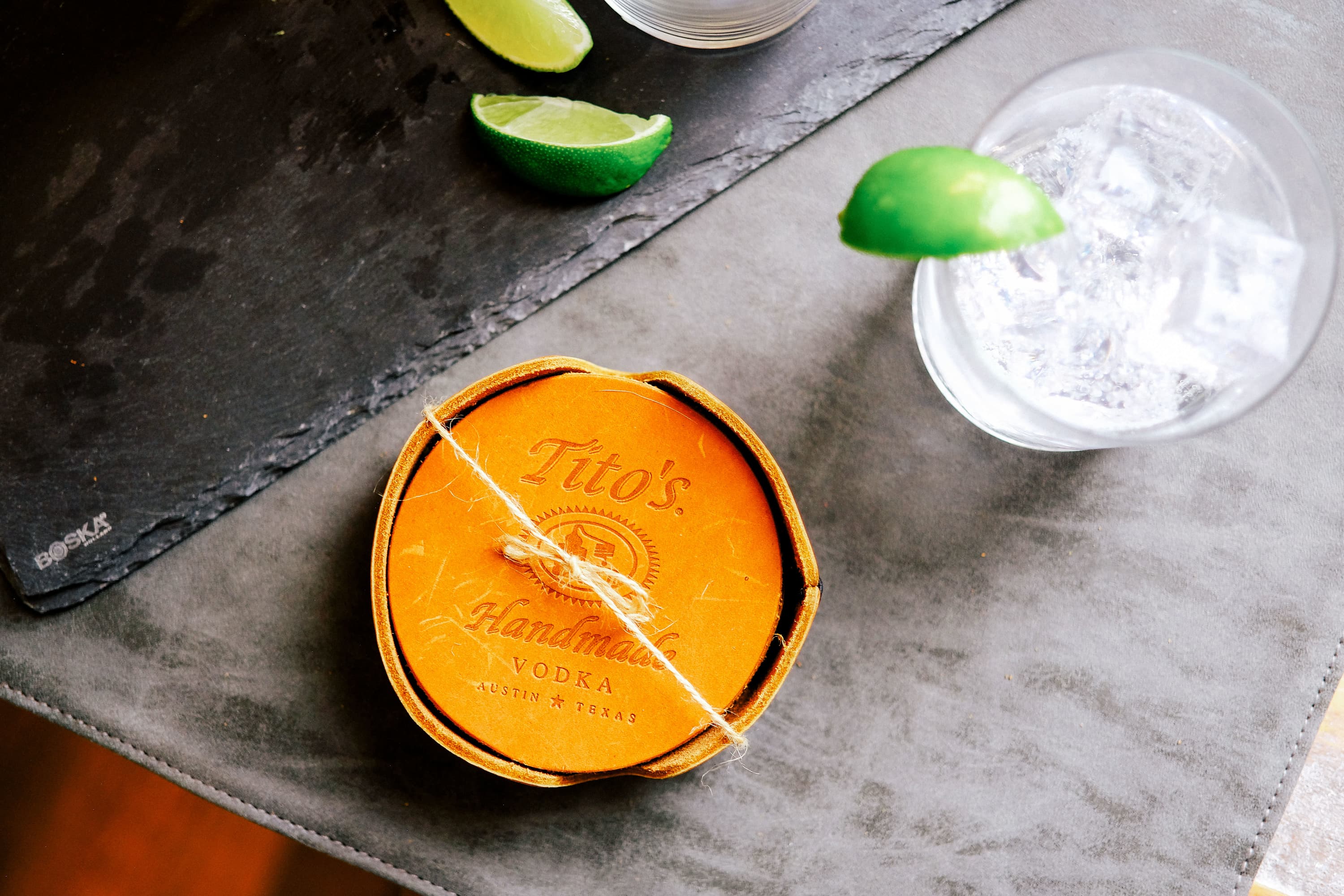 Tito's Leather Coaster Collection on a table with a cocktail