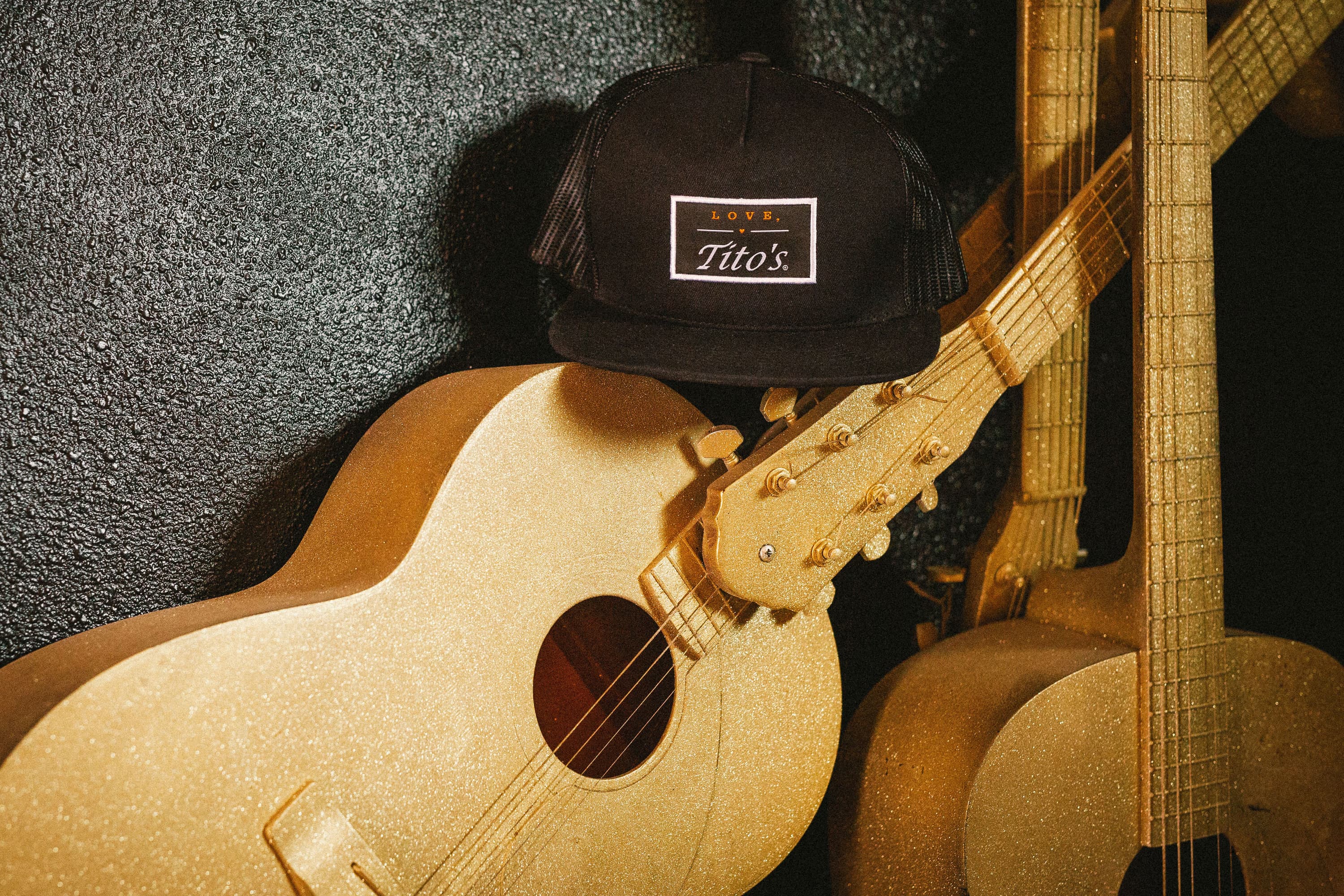 Love, Tito's Patch Hat sitting on copper painted guitars
