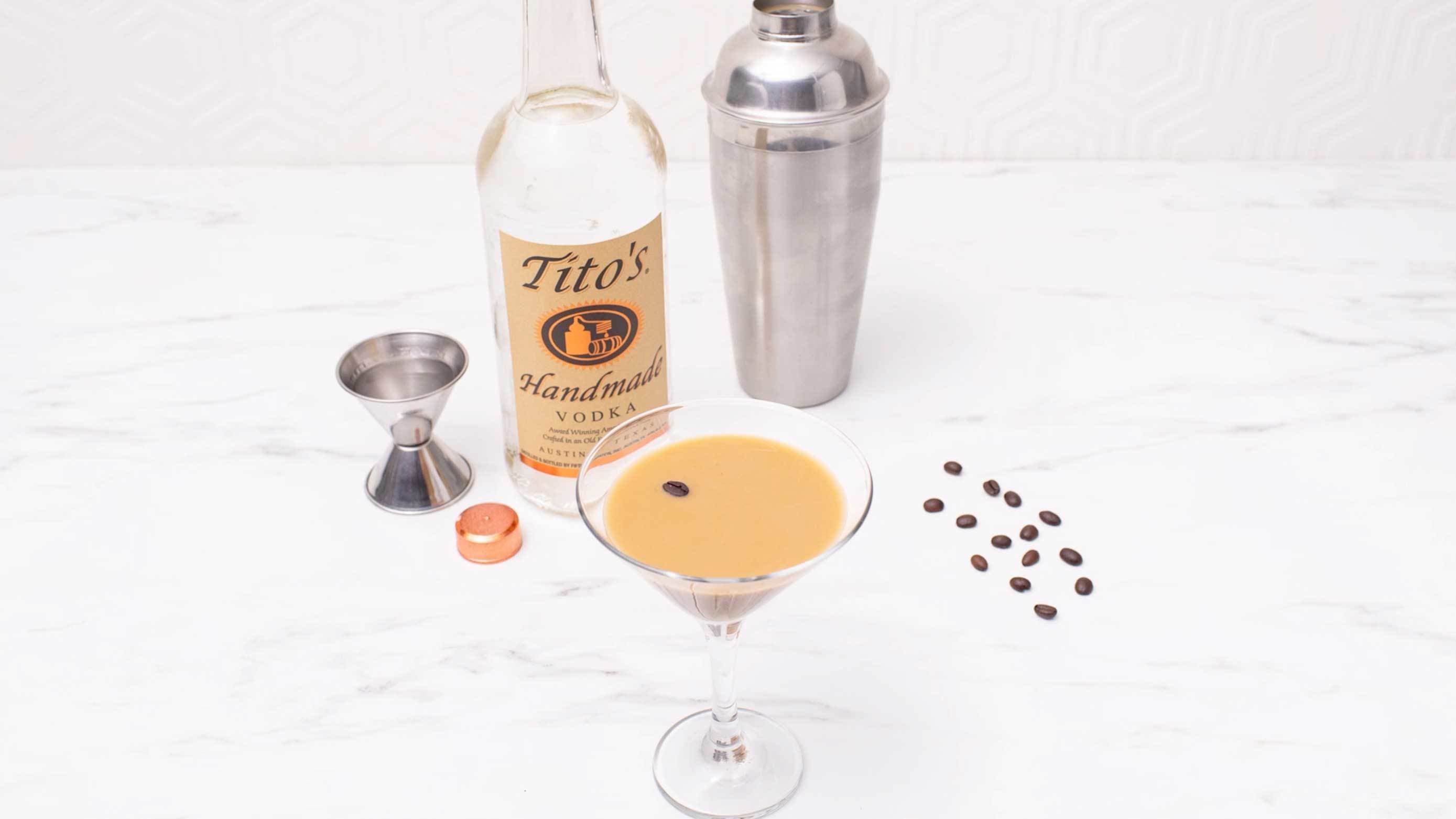 Tito's Espresso Martini garnished with espresso beans next to a bottle of Tito's Handmade Vodka
