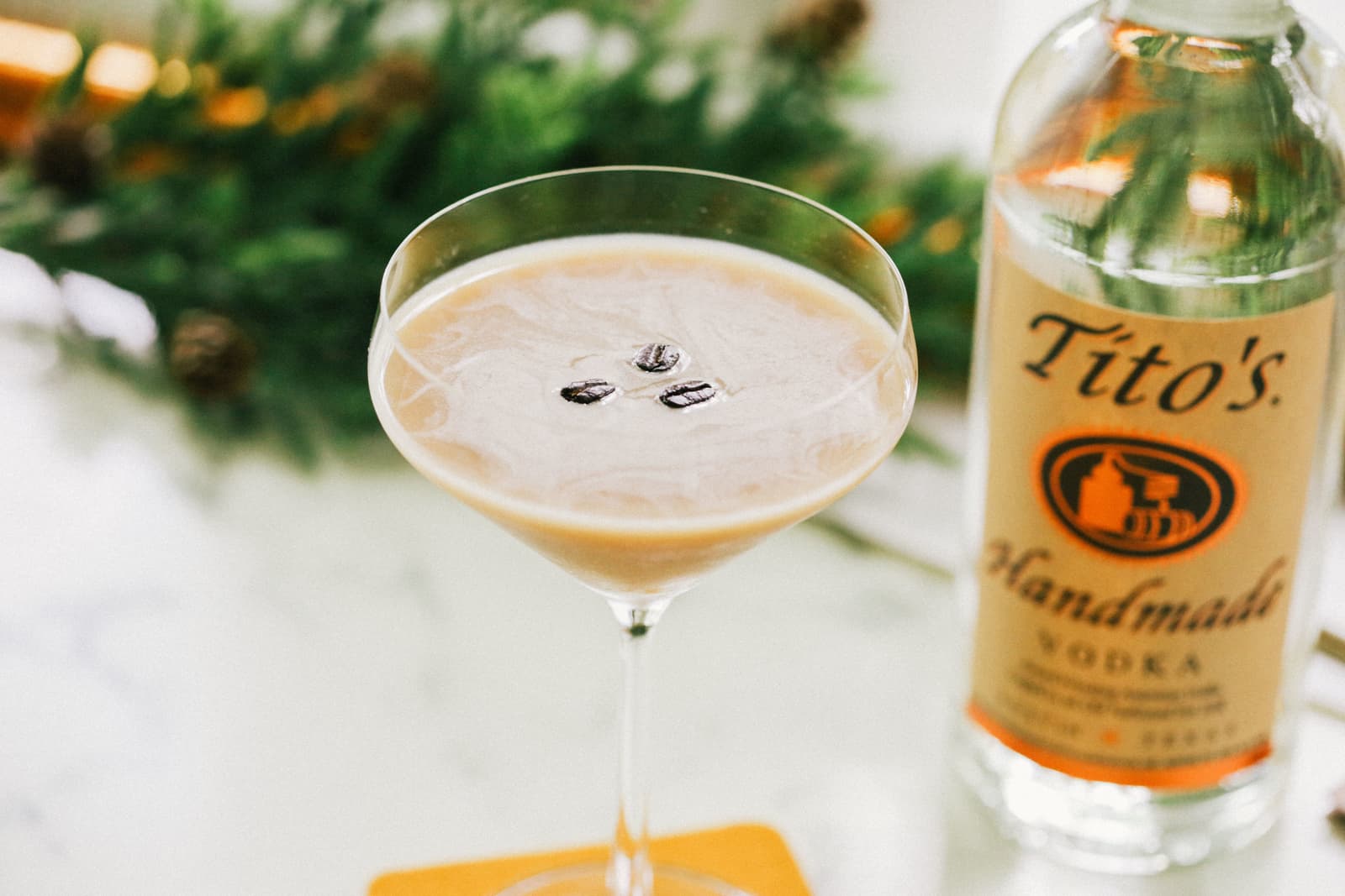 Tito's Espresso Martini garnished with three espresso beans next to a bottle of Tito's Handmade Vodka