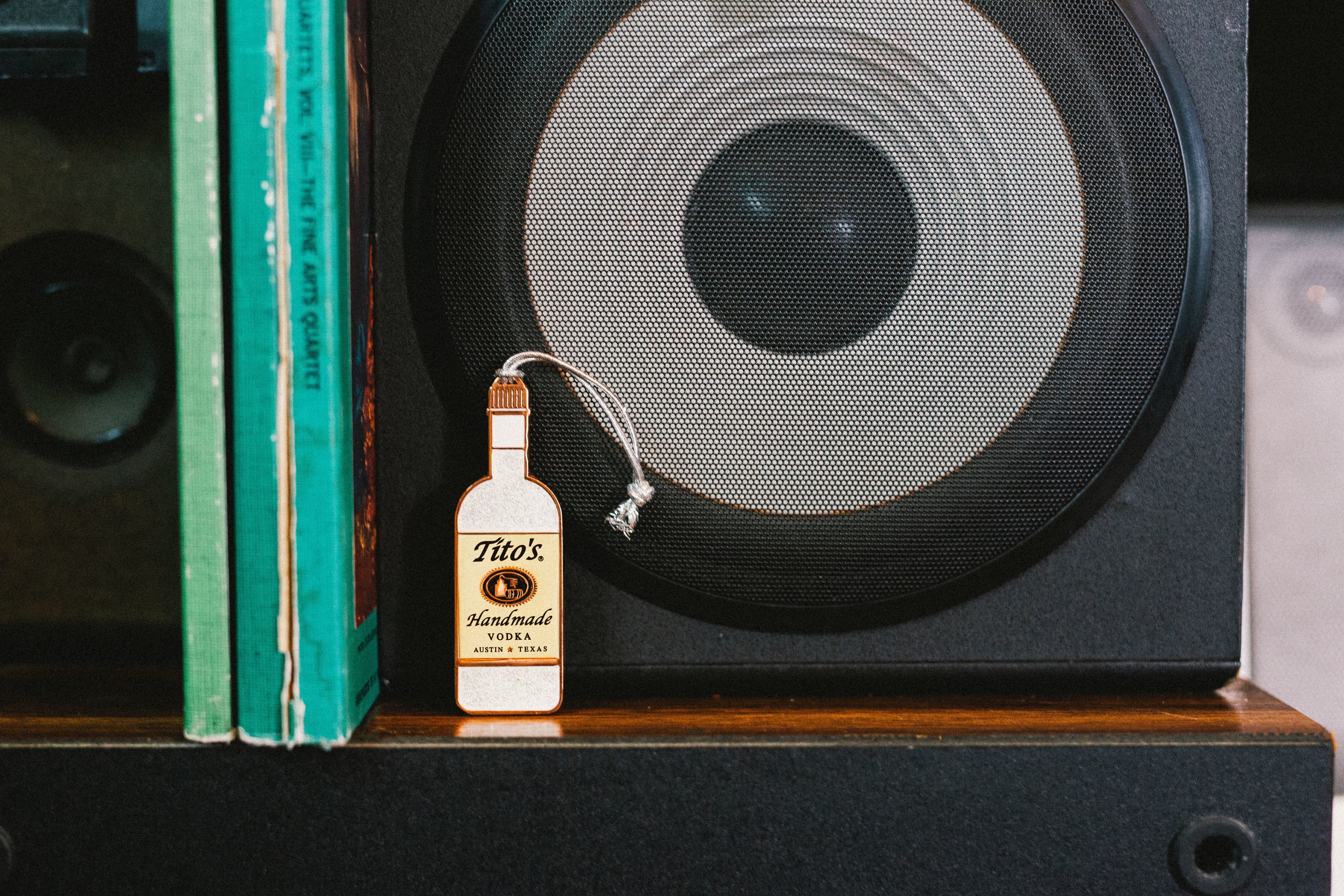 Tito's Stardust Sparkle Bottle Ornament on a bookshelf in front of a speaker