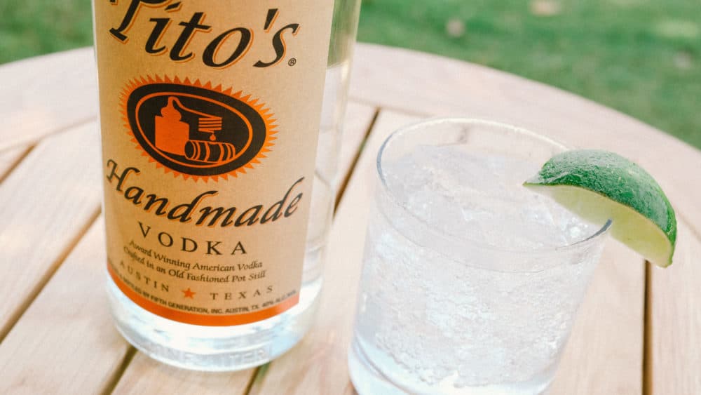 Tito's Vodka bottle next to a Tito's Soda Lime in a rocks glass