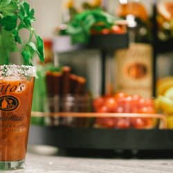 Bloody Mary being poured into Tito's Pint Glass with tray of garnishes in the background