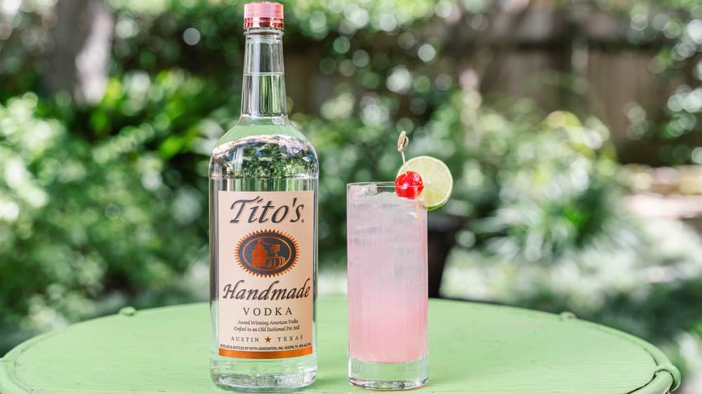 Tito's Cherry Limeade cocktail in a tall glass garnished with a lemon wheel and a cherry