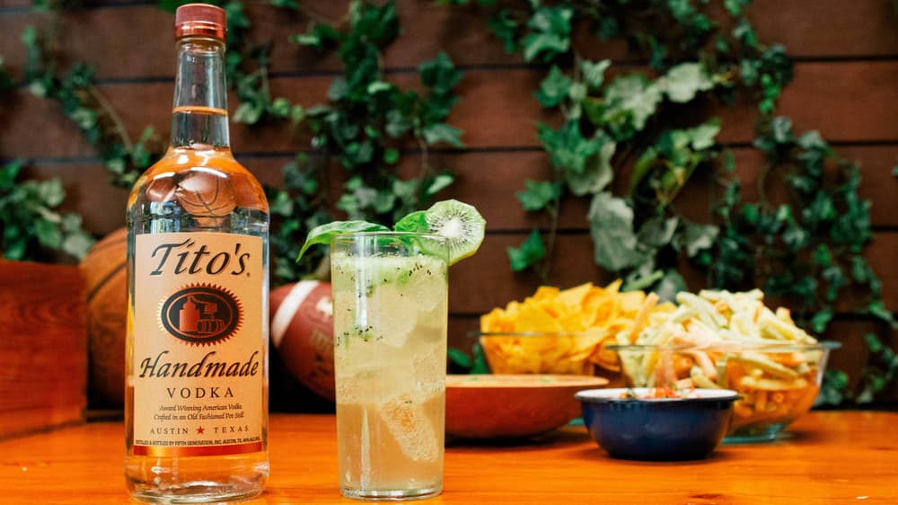 Tito's Vodka bottle next to Kiwi Kickoff in a tall glass