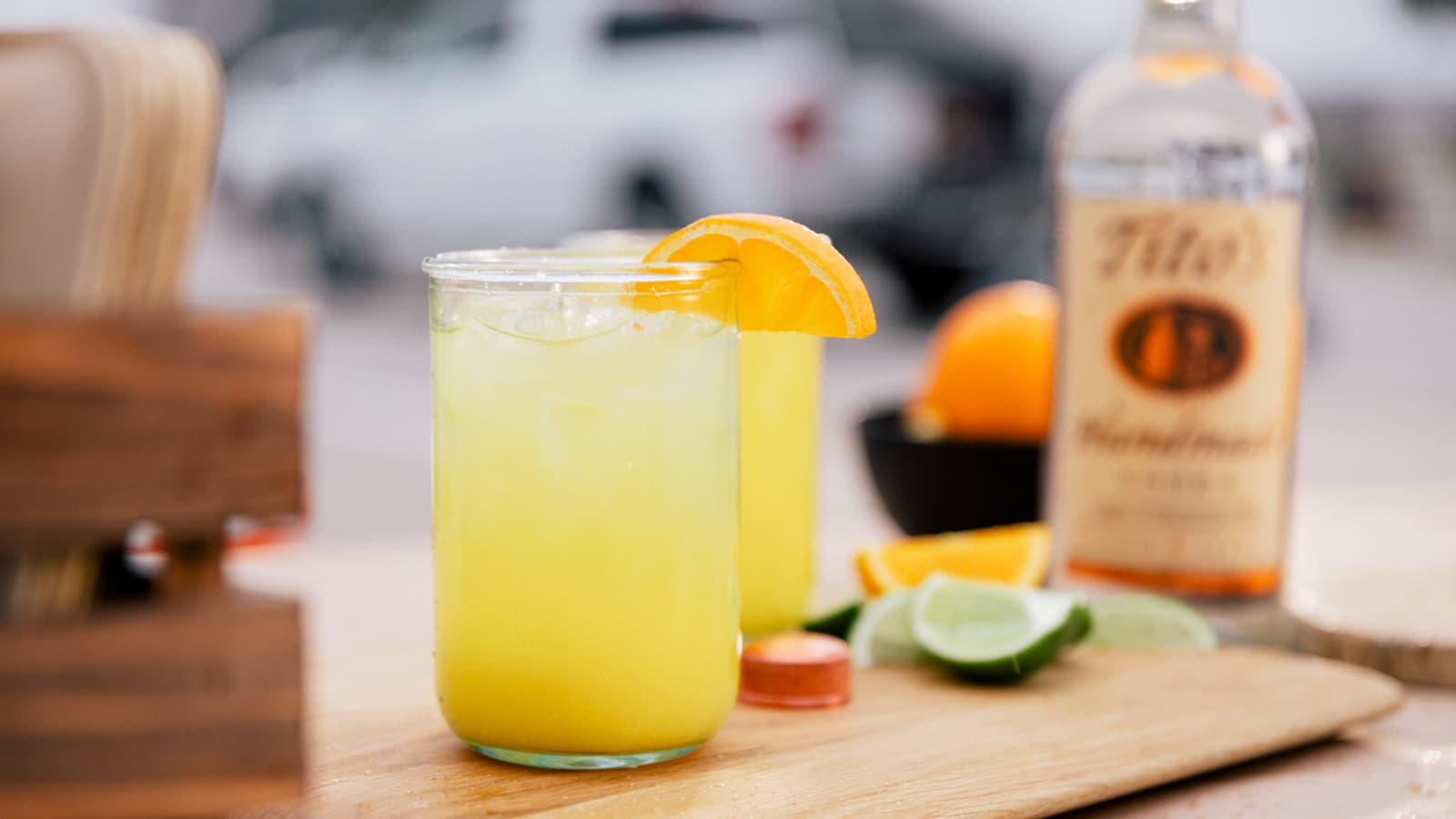 Tito's Orange Splash cocktail on a cutting board with a lime