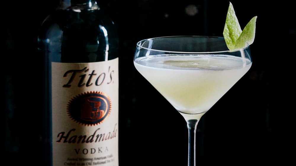 Tito's Pear Blossom in a martini glass next to a bottle of Tito's Vodka