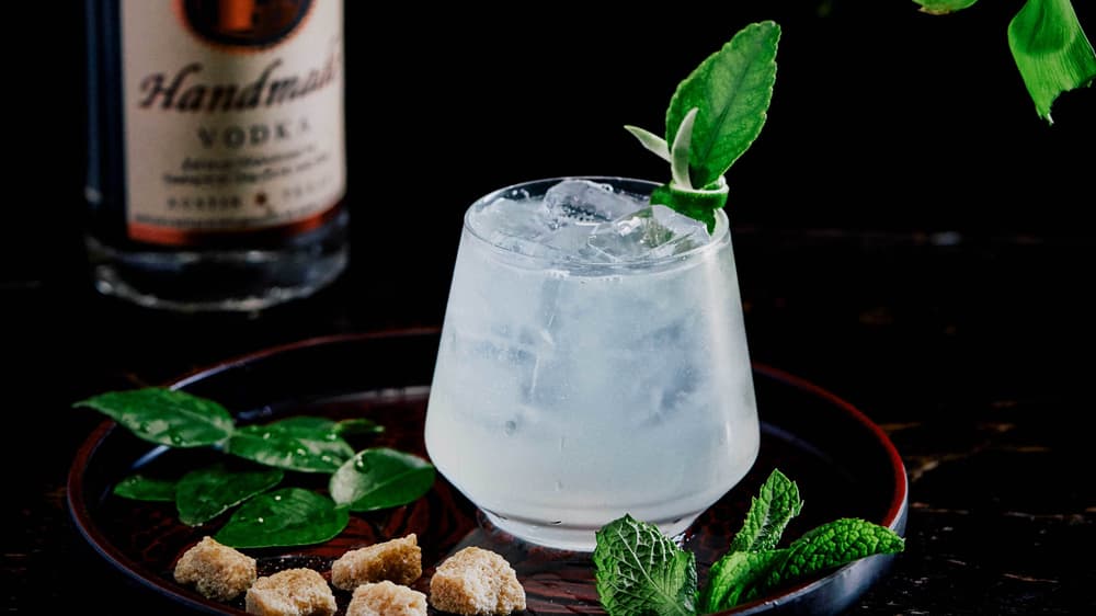 Tito's Sake Club in a stemless wine glass garnished with mint and lime leaves