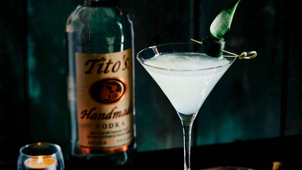 Tito's Saketini in a martini glass next to a Tito's Vodka bottle