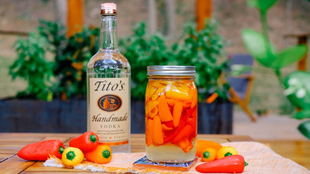 Titos Sweet Pepper Infusion in a mason jar next to a bottle of Tito's Vodka