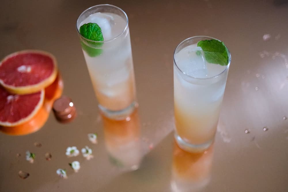Two Tito's Texas Sipper cocktails in tall glasses with sliced grapefruit