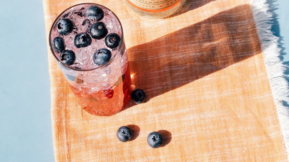 Red, White & Boozy in a tall glass next to a Tito's Vodka bottle by a swimming pool