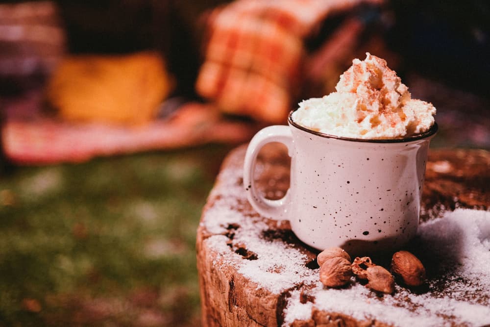 Cocktail in a mug topped with whipped cream sitting on a tree stump